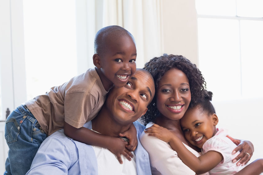 Parents with son and daughter sitting on the couch. Click to learn about life insurance and financial planning.